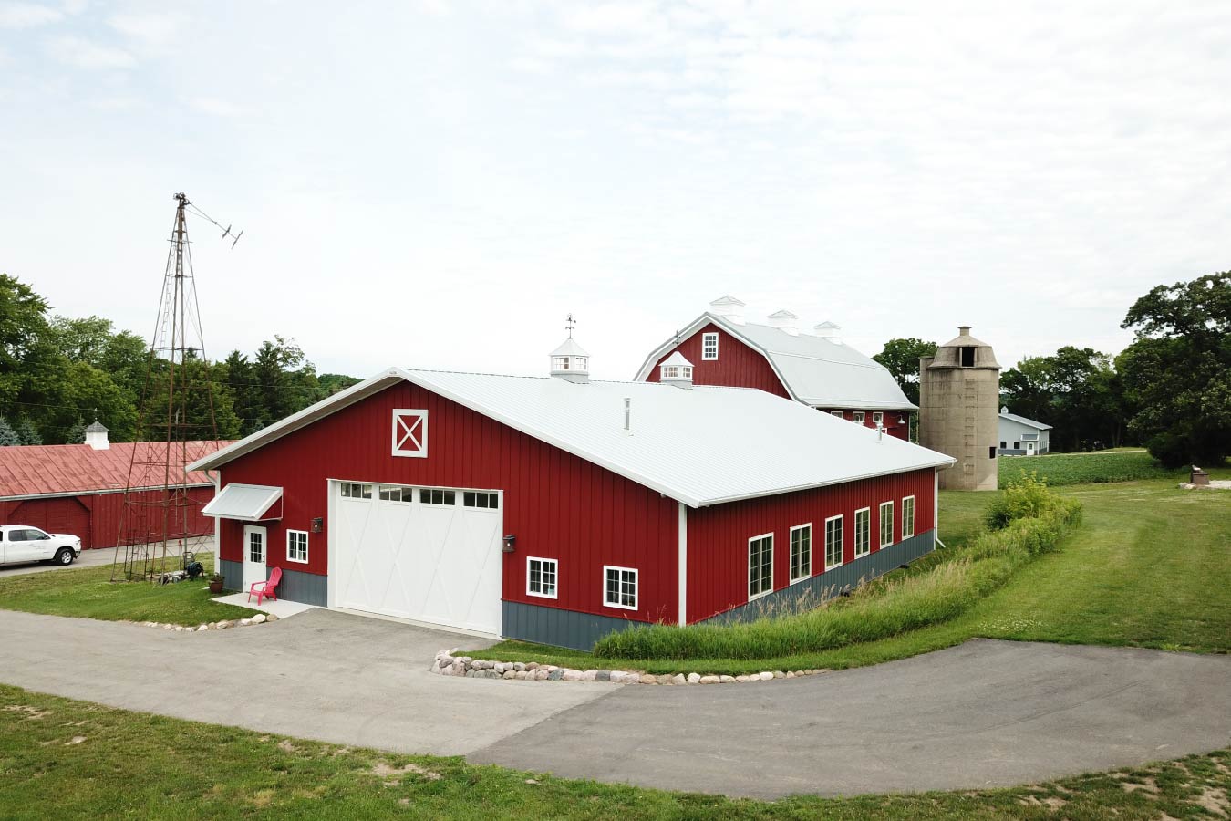 car collection garage with red steel siding, white overhead door, side windows, and cupolas