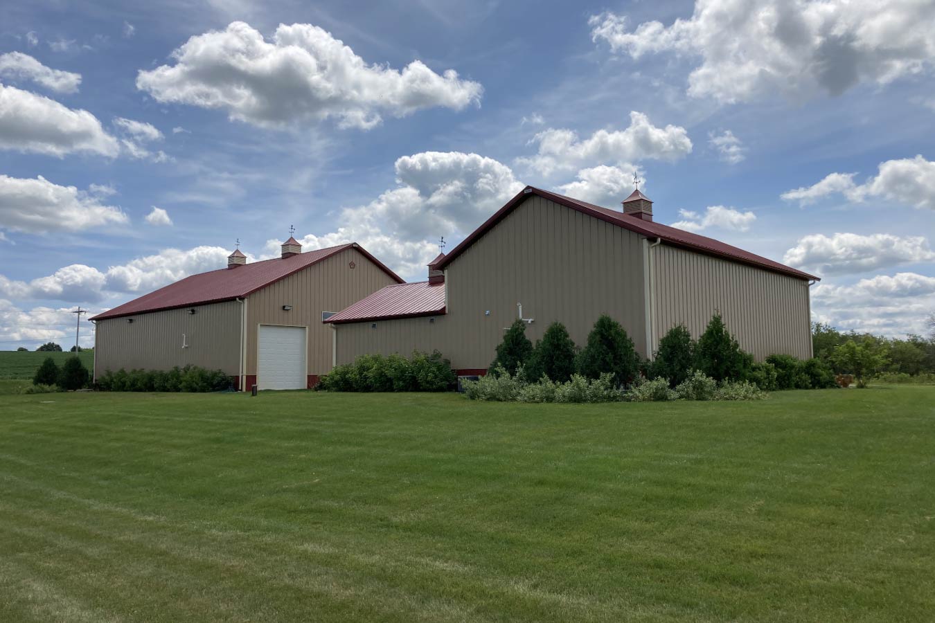 Commercial storage condo buildings with connected layout, cupolas, overhead door access, and landscaped exterior- Rear View