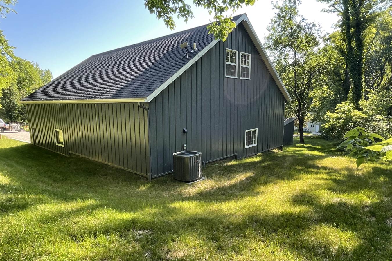 garage with living quarters rear side view with steel siding, loft windows, and post frame construction