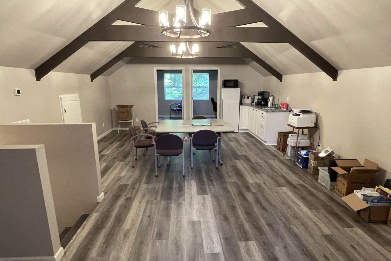 garage with living quarters loft featuring open floor plan, exposed beams, and kitchenette