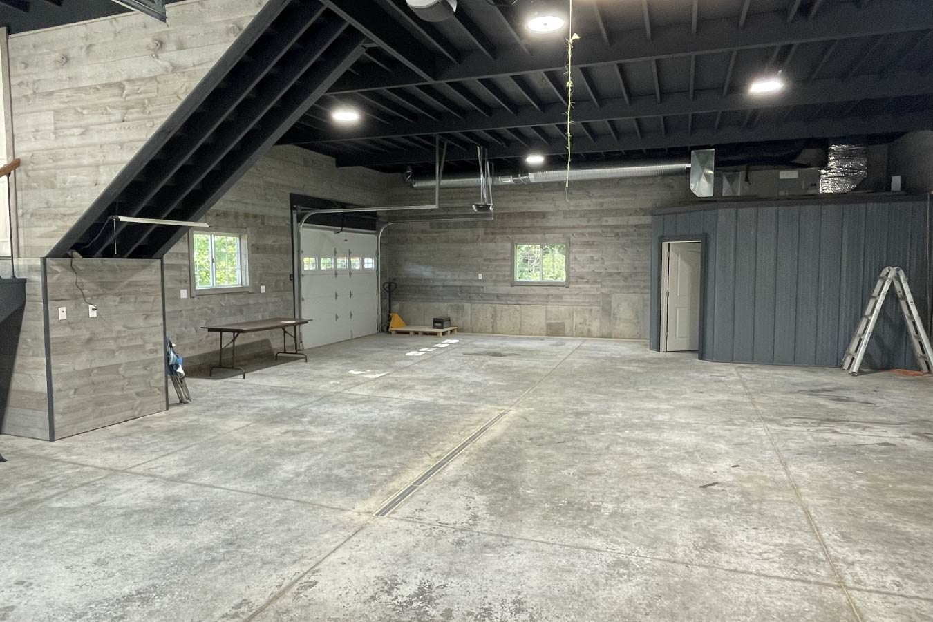 garage with living quarters interior showing open garage space, staircase, and post frame construction