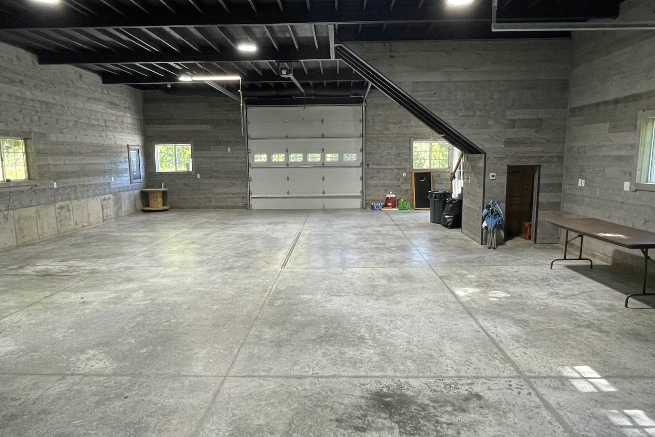 garage with living quarters interior showing open garage space, staircase, and post frame construction