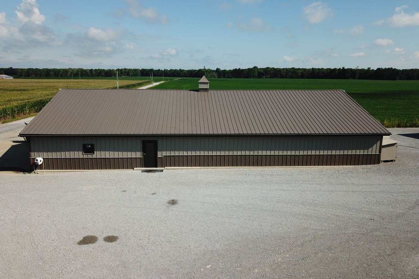 Grain farm pole barn used as an agricultural storage building surrounded by crop fields with Side Walk Door