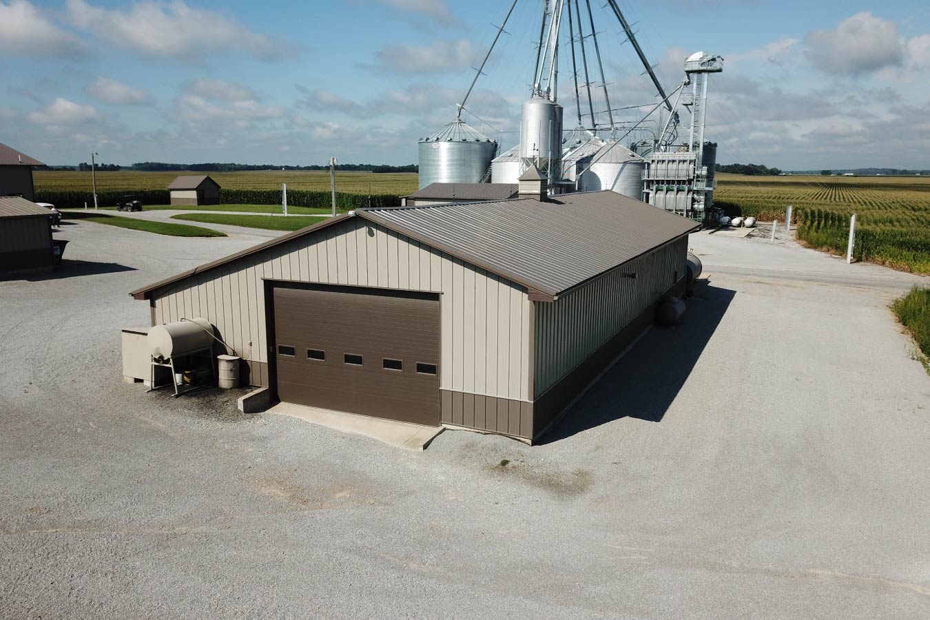 Grain farm pole barn used as an agricultural storage building beside grain bins and handling equipment