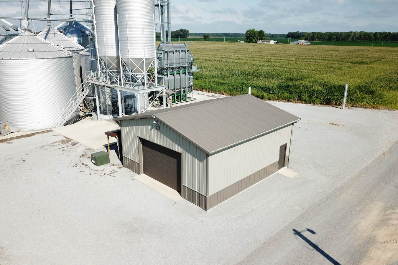 Grain farm pole barn used as an agricultural storage building beside grain bins and grain handling equipment with Overhead Door and Side Walk Door