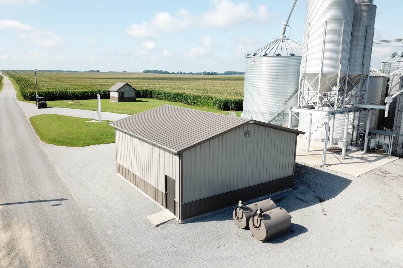 Grain farm pole barn used as an agricultural storage building beside grain bins and corn fields