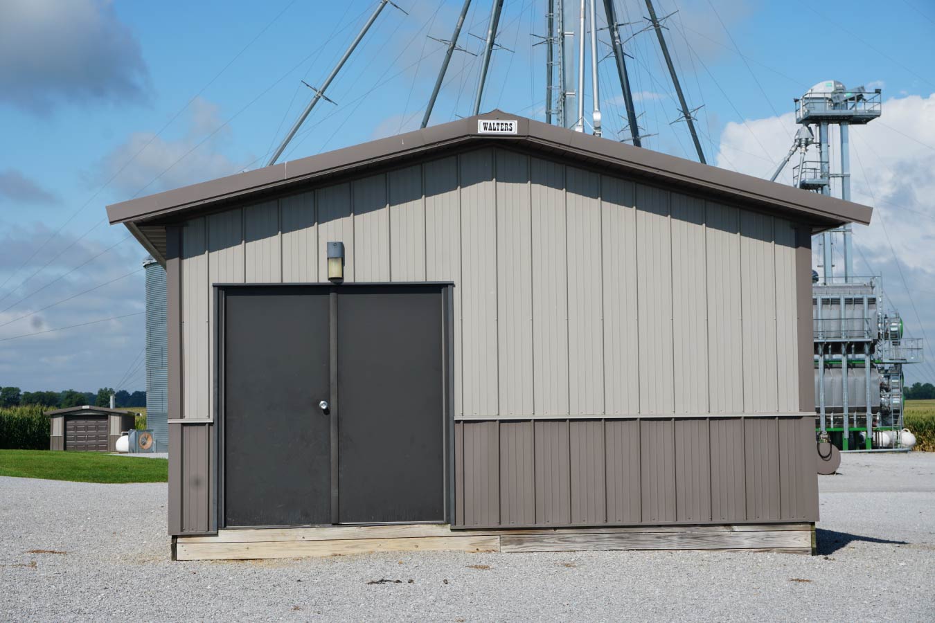 Small grain farm pole barn used as an agricultural storage building beside grain handling equipment Dual Doors on Smaller Storage Building