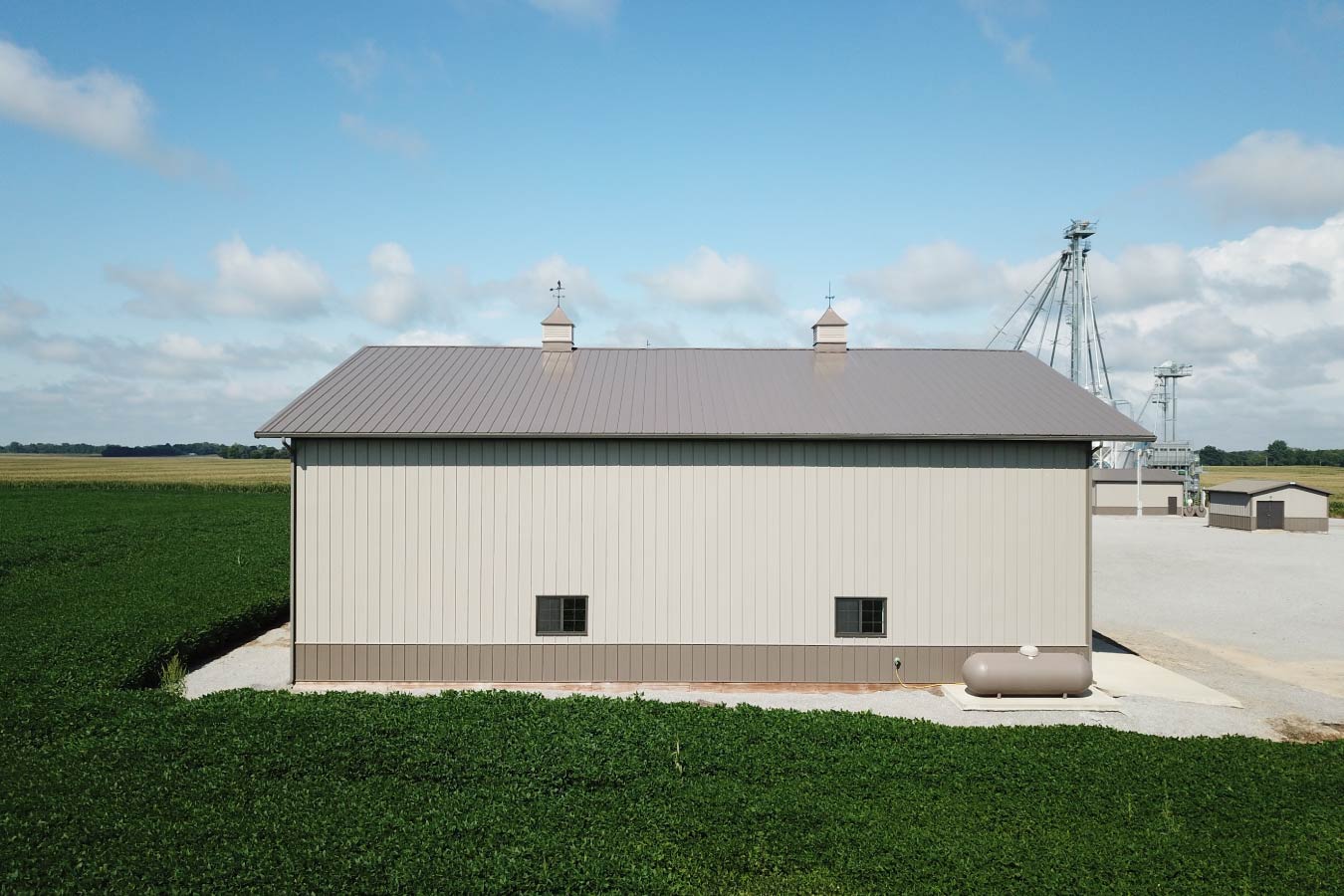 Side view of agricultural pole barn used as a farm equipment storage building beside crop fields