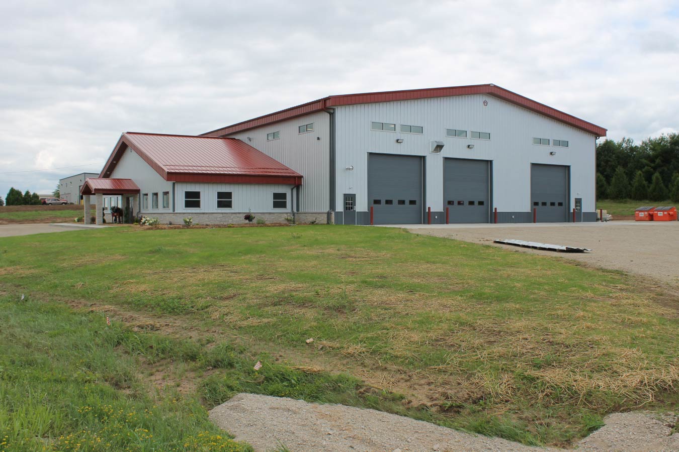 large industrial metal building with red steel roof gray overhead doors and office entrance
