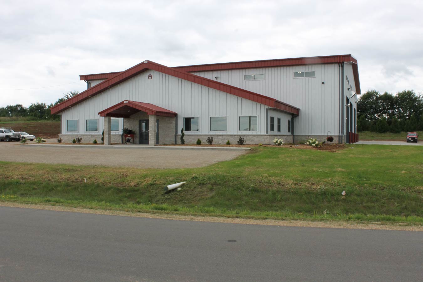 large industrial metal building with red steel roof covered entrance and office windows
