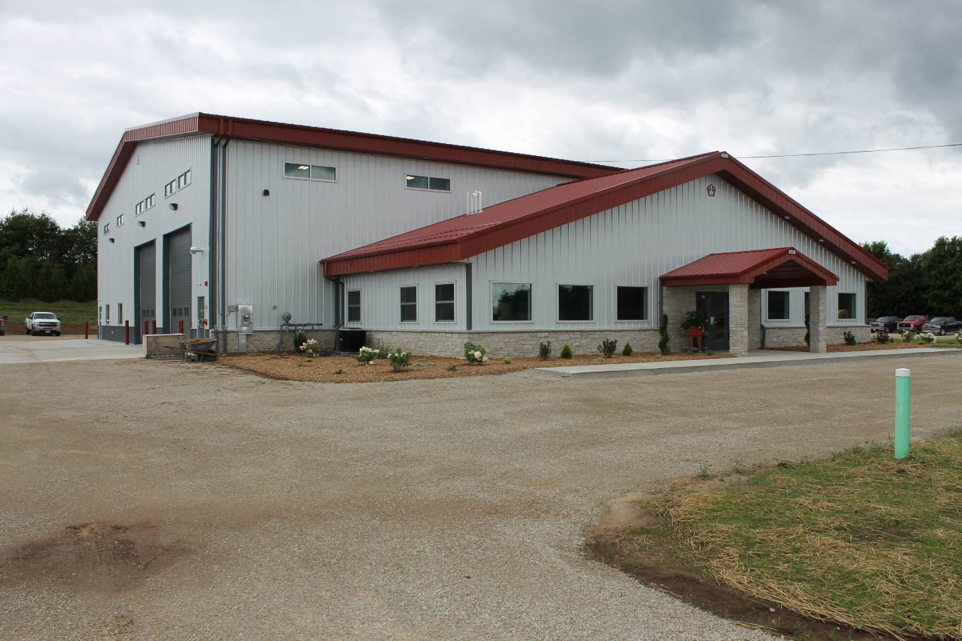 large industrial metal building with red steel roof covered entrance and office windows