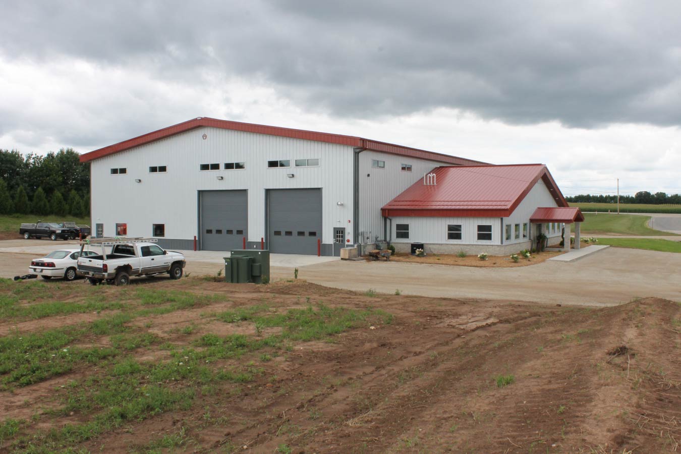 large industrial metal building with red steel roof gray overhead doors and office entrance