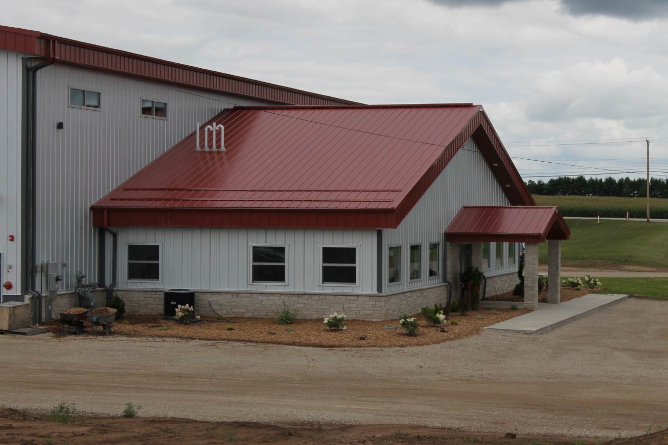 industrial metal building with red steel roof office entrance canopy stone wainscot and white steel siding