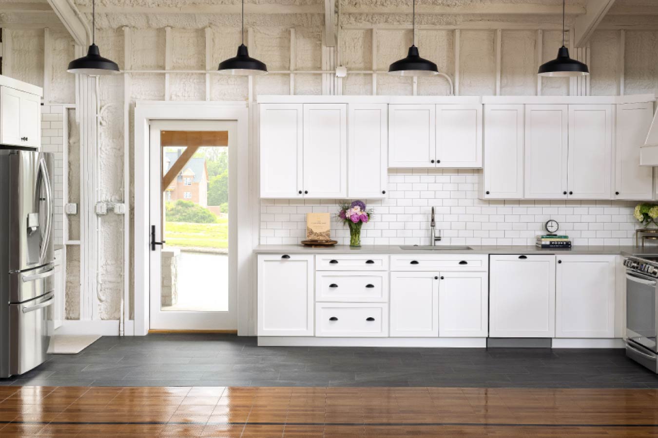 Kitchen area inside the Keene Ranch event barn with white cabinets, subway tile backsplash, and stainless steel appliances. Interior Kitchen