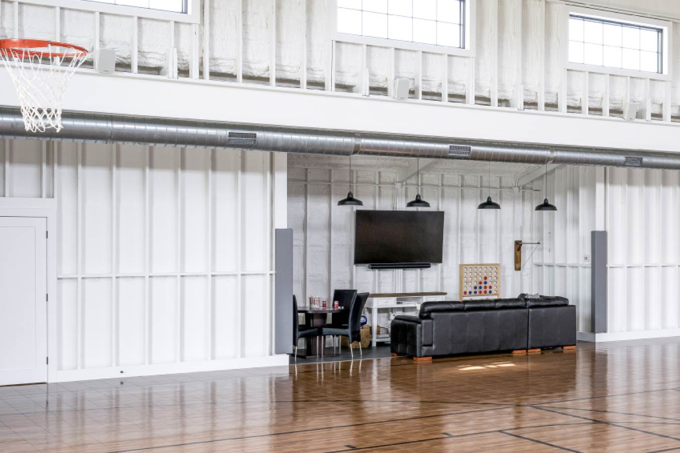 Lounge area inside the Keene Ranch event barn with seating, TV, and recreation court flooring. Lounge Area