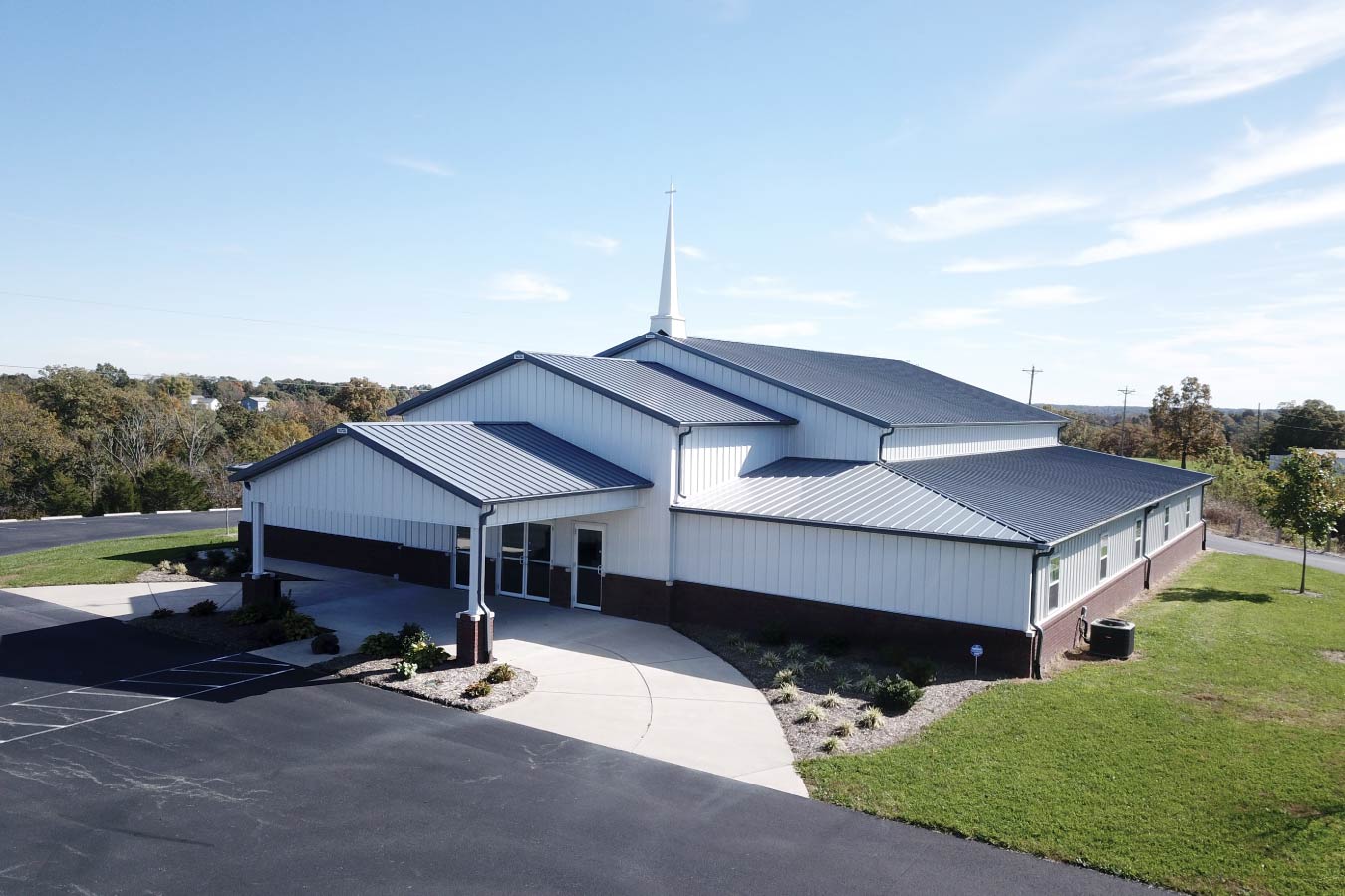 Pleasant Hill Christian Church post frame church building with white steel siding, brick wainscot, gray metal roof, and steeple.