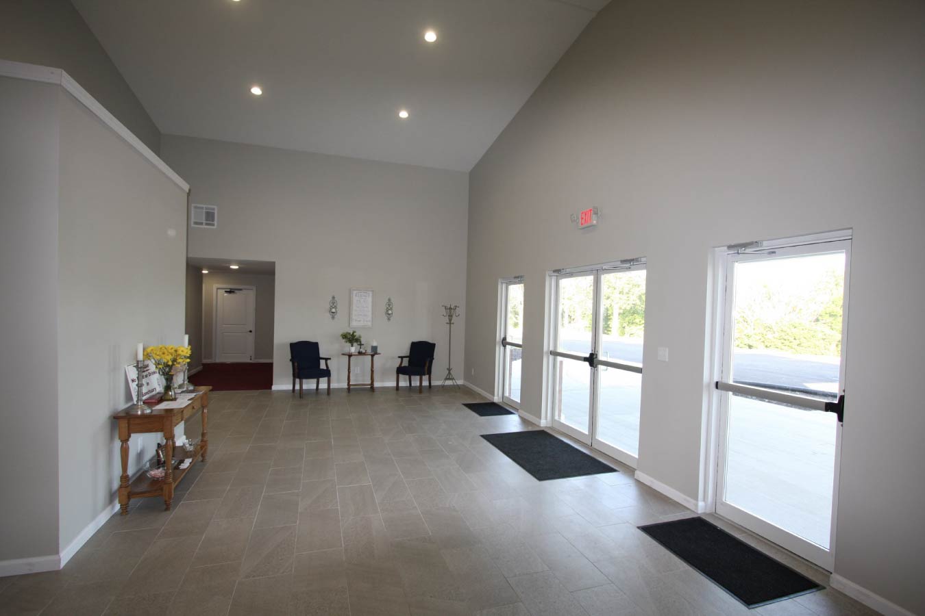 Church lobby interior with glass entry doors, tile flooring, recessed lighting, and seating area.