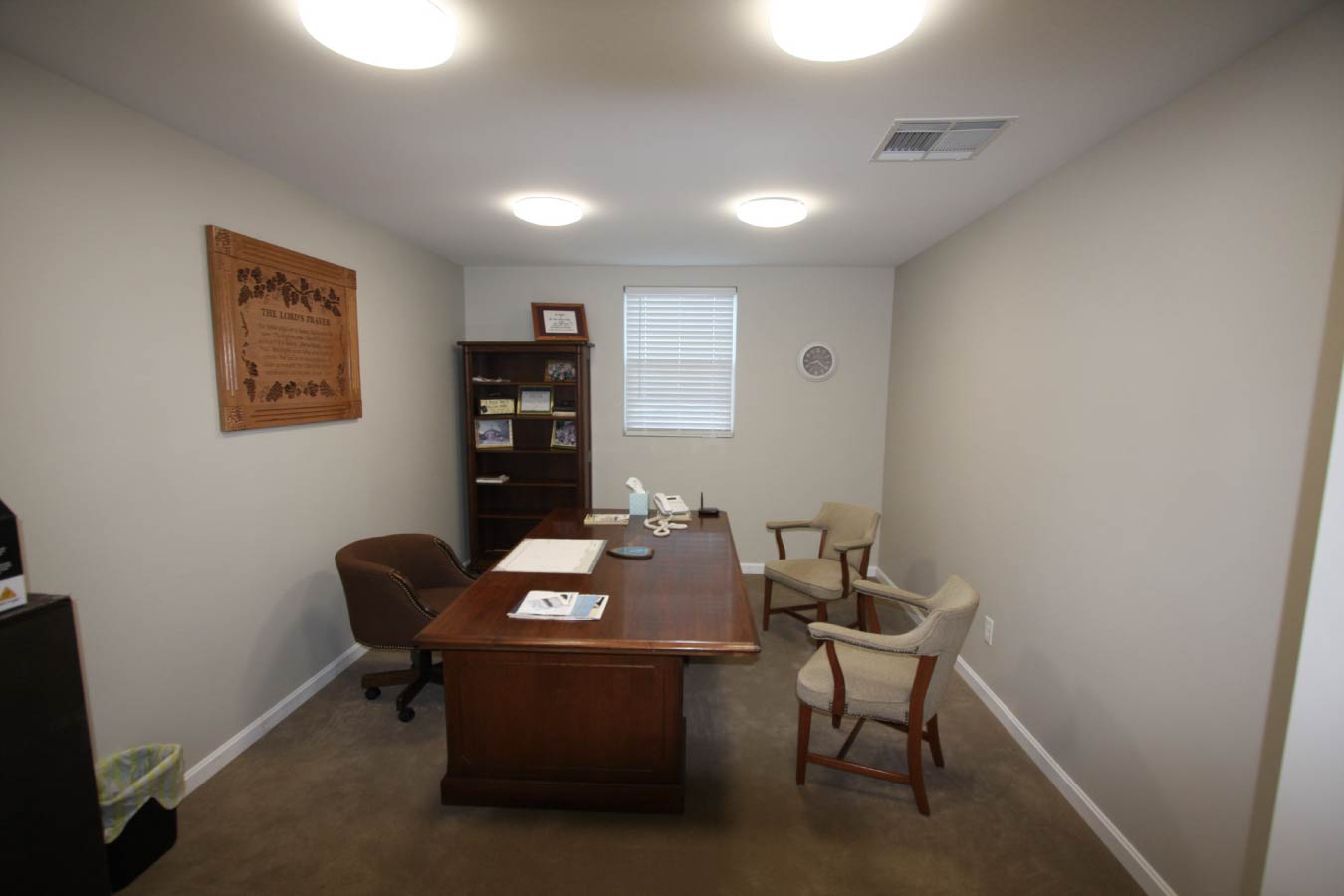 Church office interior with wooden desk, chairs, bookshelf, and window. Office Space