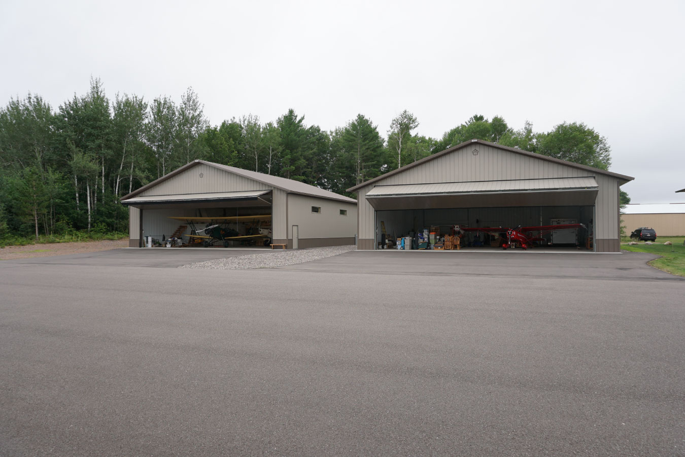 airport hangar buildings with airplanes inside and large open hangar doors on paved apron