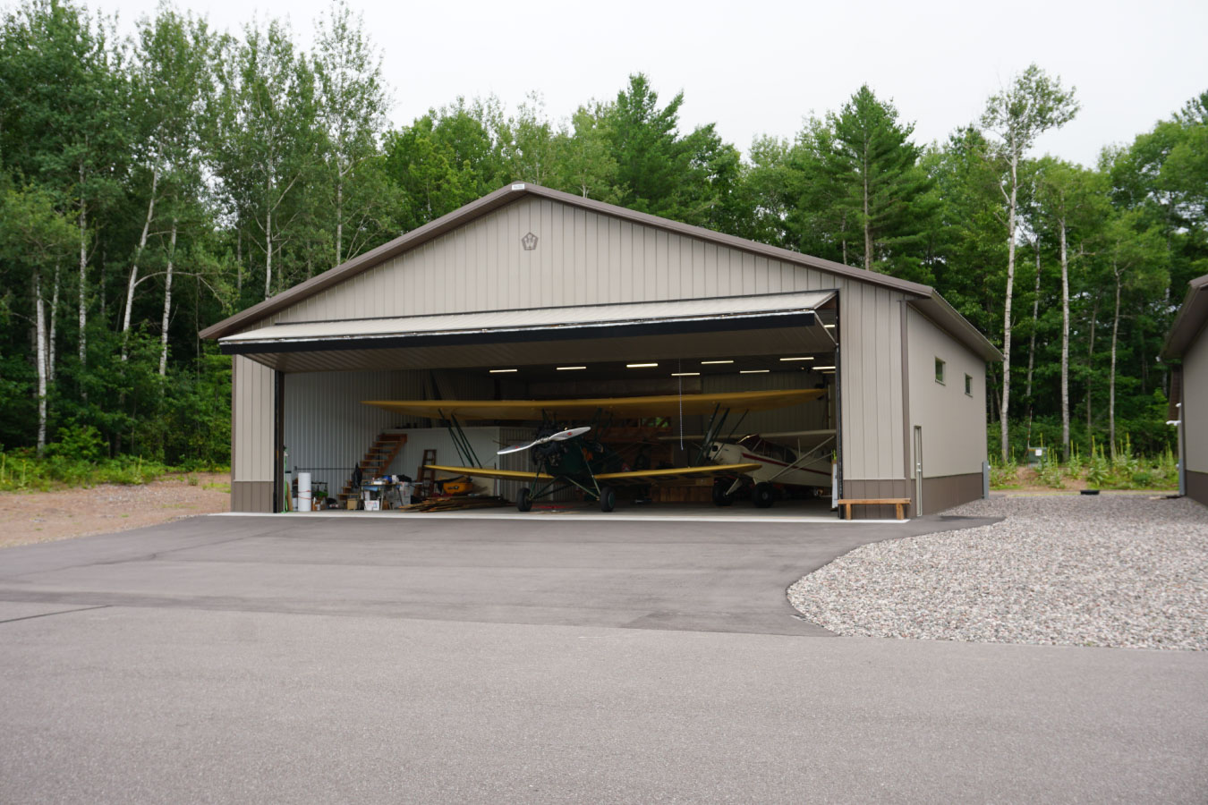 airport hangar with airplane inside and large open aircraft door in wooded setting