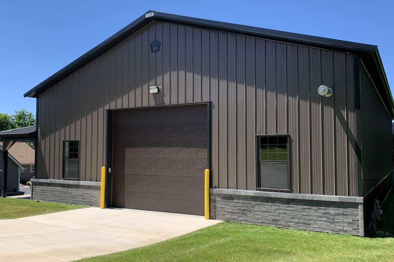 pole barn garage overhead door with protective bollards and exterior lighting