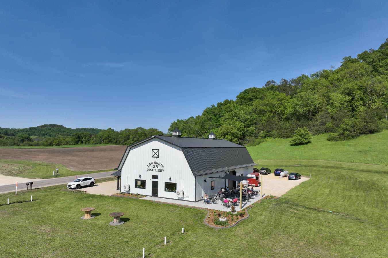 98-1449 Township 23 Distillery commercial building distillery with gambrel roof white steel siding outdoor patio seating and rural setting