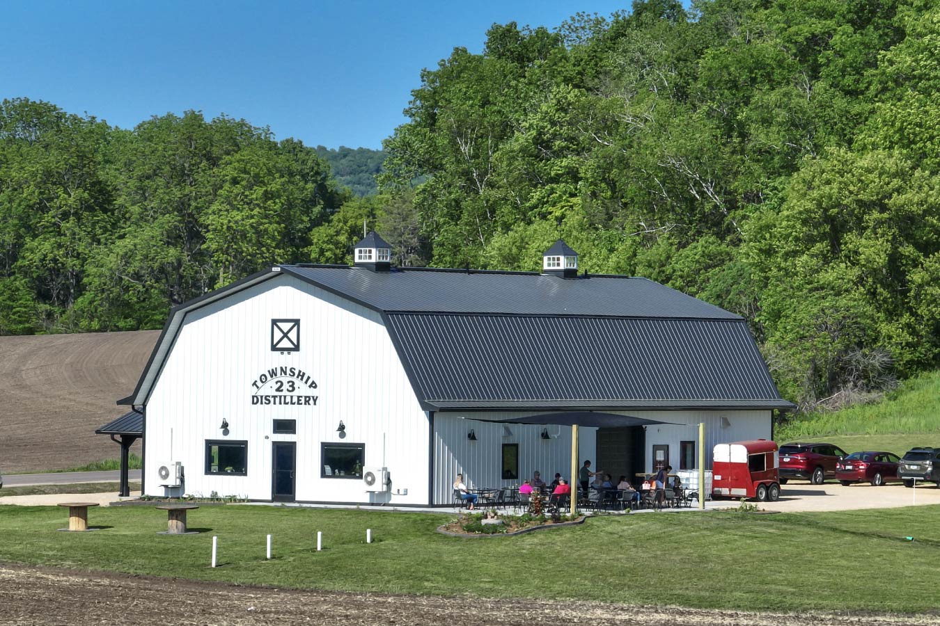 commercial building distillery with black gambrel roof white steel siding cupolas and outdoor patio seating