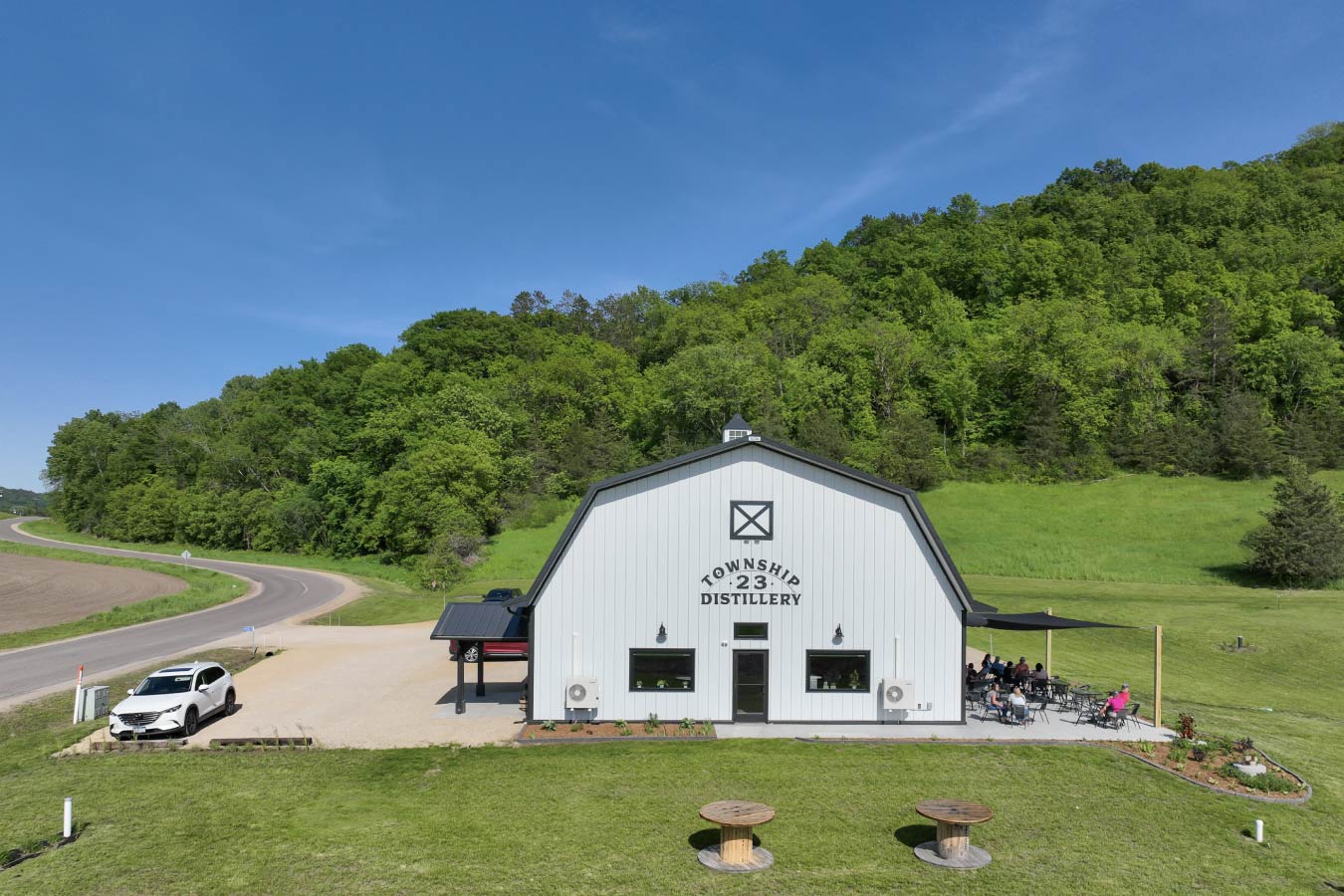 commercial building distillery with gambrel roof white siding front entrance and outdoor patio seating
