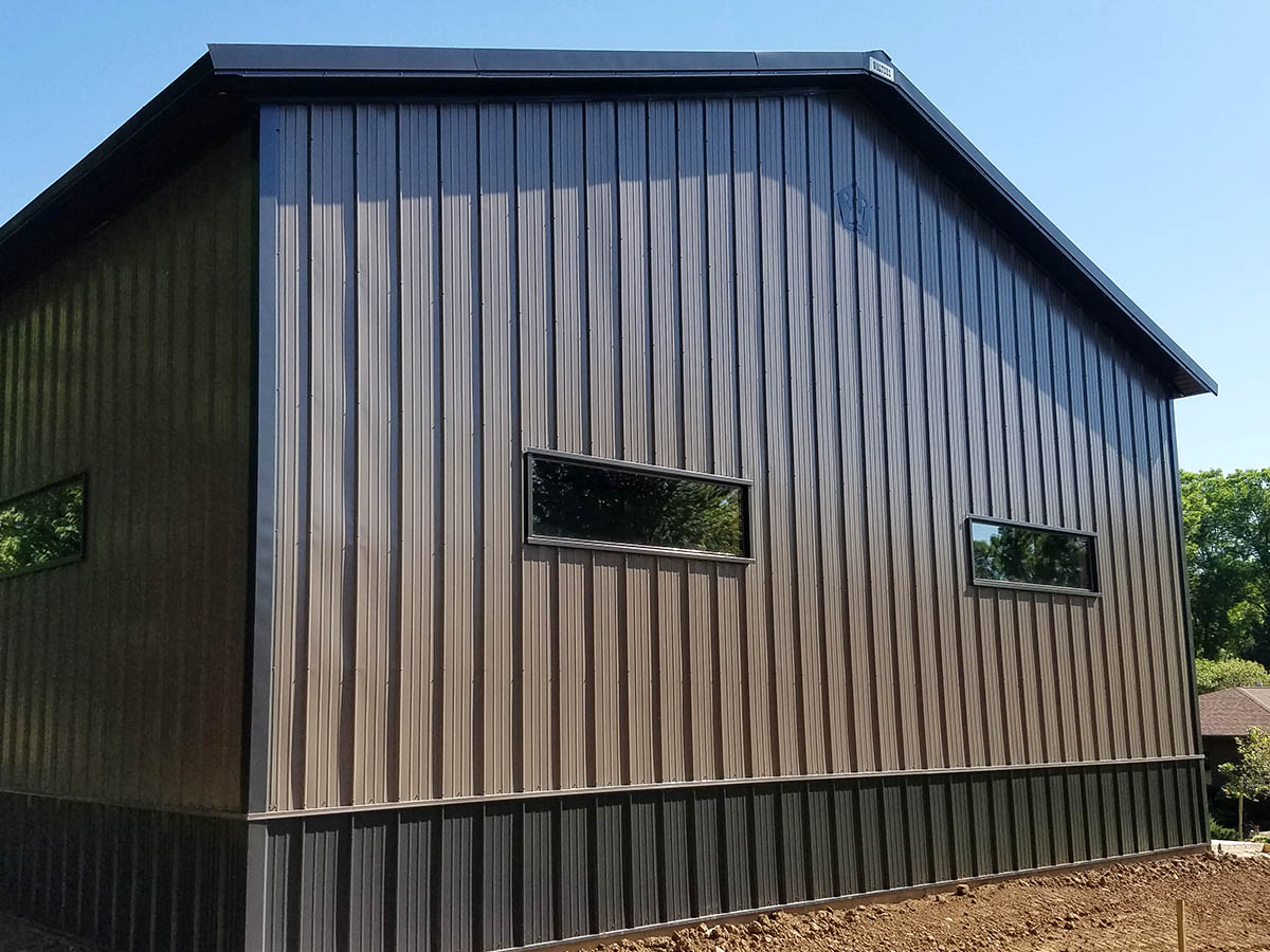 Steel equipment storage building with horizontal windows and wainscot siding in rural setting