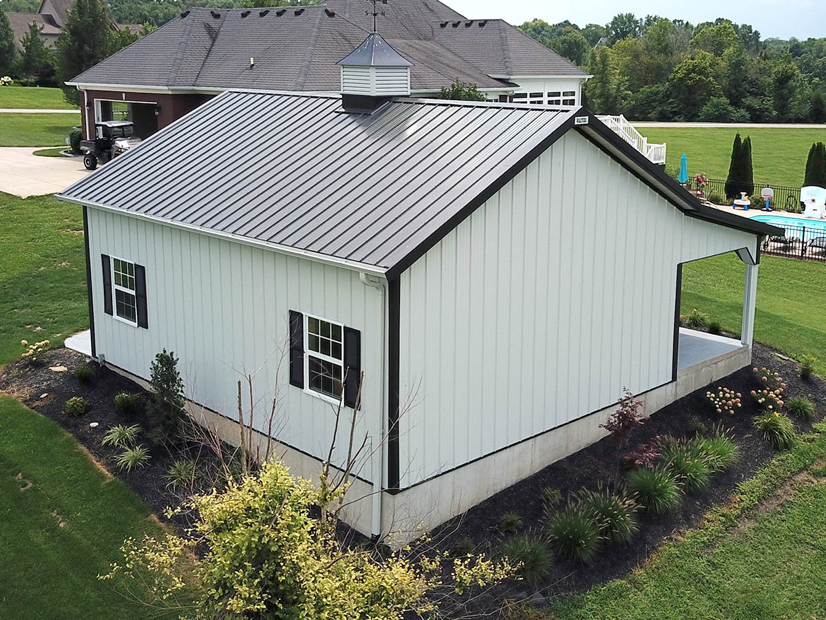 Post frame building with steel siding, windows, cupola, and lean to porch