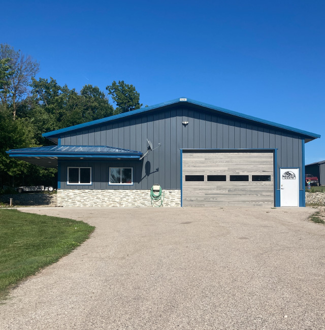 Lake House Garage with Blue Steel Siding and Stone Wainscot | Walters Buildings Lake house garage with blue steel siding, stone wainscot, and overhead garage door