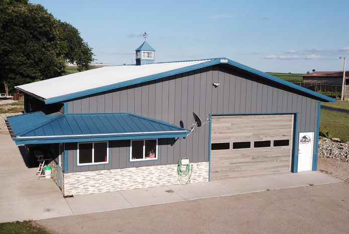 Lake House Garage with Blue Roof, Stone Wainscot, and Covered Porch | Walters Buildings Lake house garage exterior with blue roof, stone wainscot, and overhead garage door