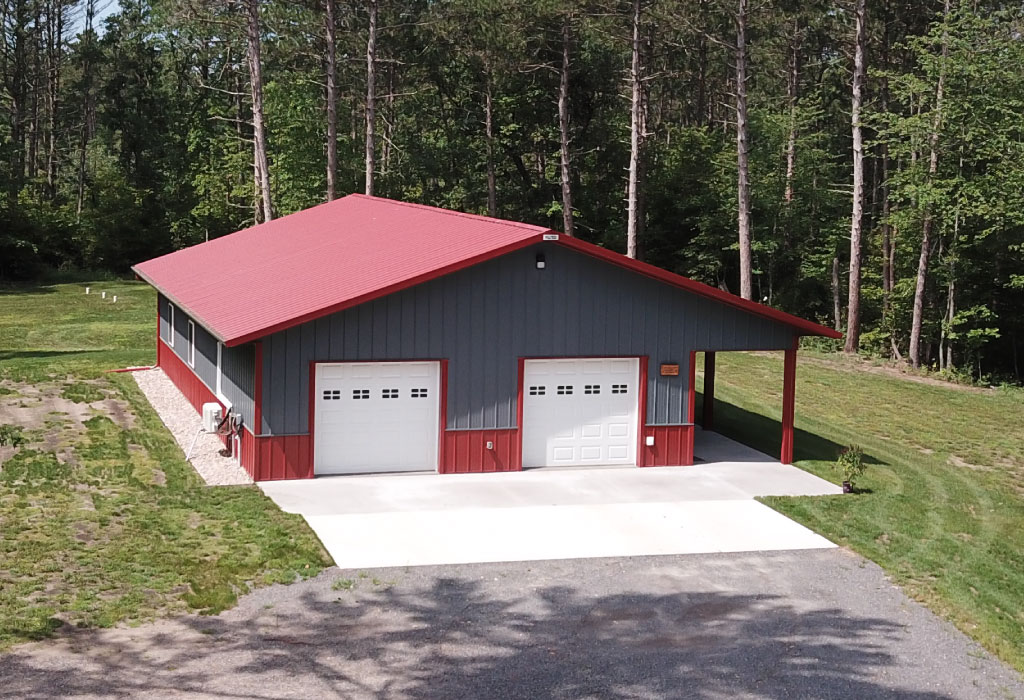 Post-Frame Garage with Overhead Doors and Covered Lean-To Porch Post-frame garage building with steel siding, two overhead doors, and covered lean-to porch