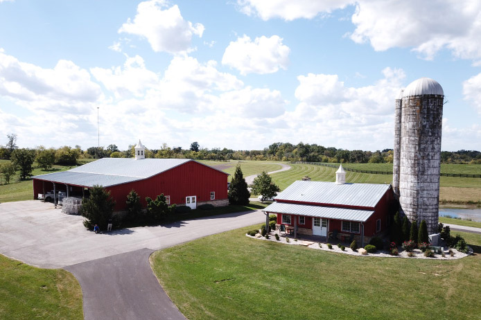 Pole barn house with red steel siding, metal roof, and farm silo on rural property