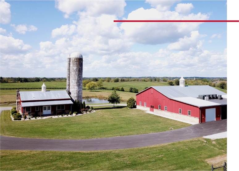 Pole barn house with red steel siding, metal roof, and farm silo on rural property