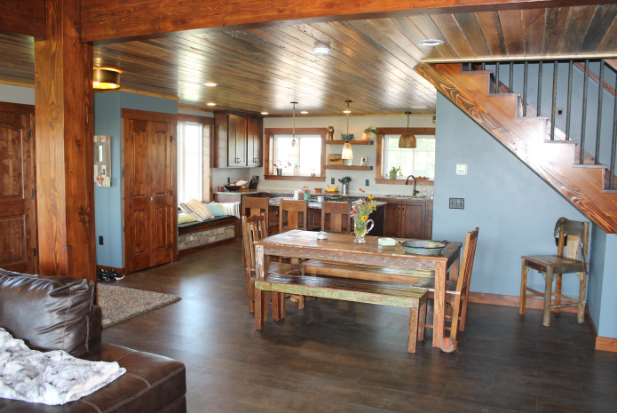 Pole barn house interior with open dining area, wood staircase, and farmhouse kitchen