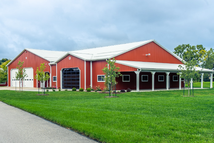 Red Pole Barn with Covered Porch and Garage Doors | Walters Buildings Red pole barn with white metal roof, overhead garage doors, and covered porch