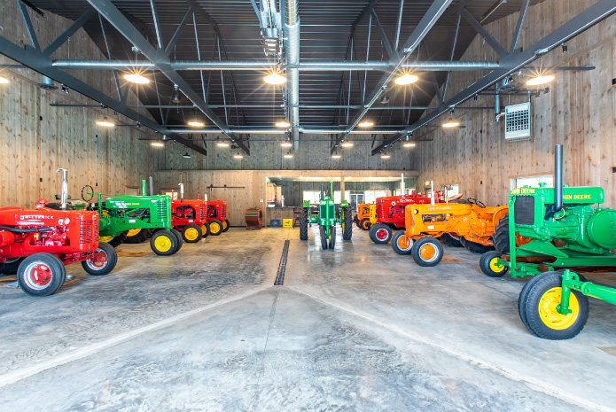Pole Barn Tractor Storage and Display Building | Walters Buildings Interior of pole barn displaying vintage tractors with wood walls and exposed steel trusses