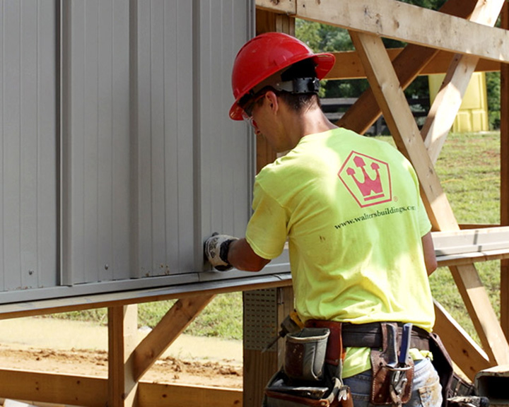 Walters Buildings crew member installing steel siding with precision during construction process