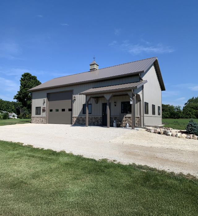 Residential Workshop with Garage Door and Covered Porch | Walters Buildings Residential workshop with metal siding, overhead garage door, covered porch, and cupola