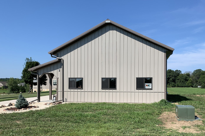 Residential Workshop with Garage Door and Covered Porch | Walters Buildings Residential workshop with steel siding, overhead garage door, covered porch, and cupola