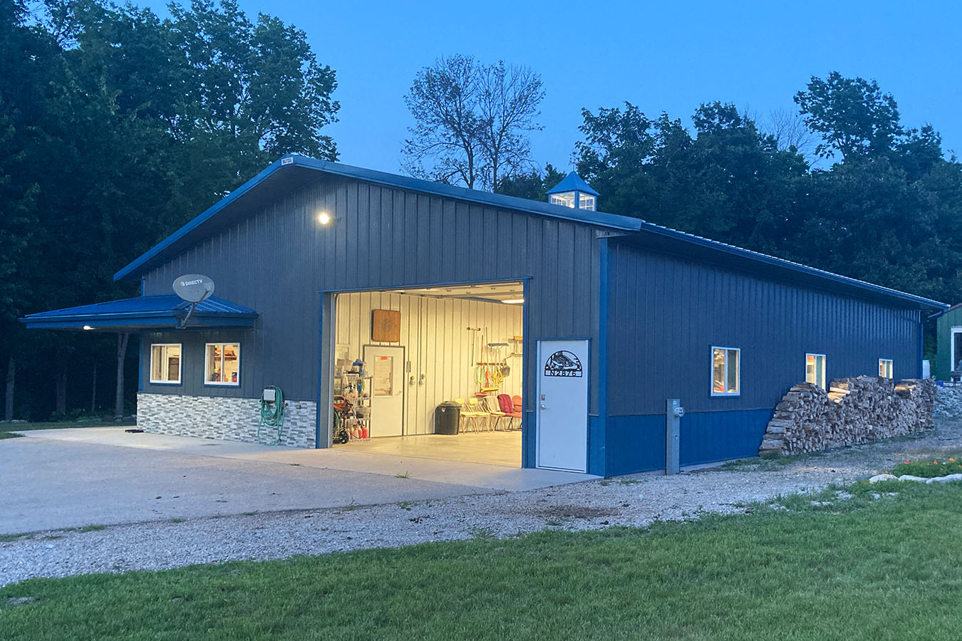 Lake house garage at dusk with open overhead door, steel siding, and cupola