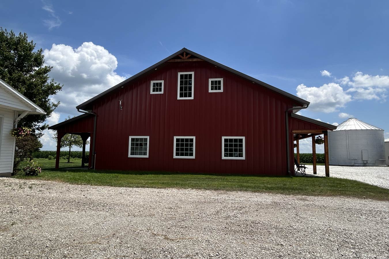 Residential workshop with red steel siding, steel roof, multiple Plyco windows, and covered side porches