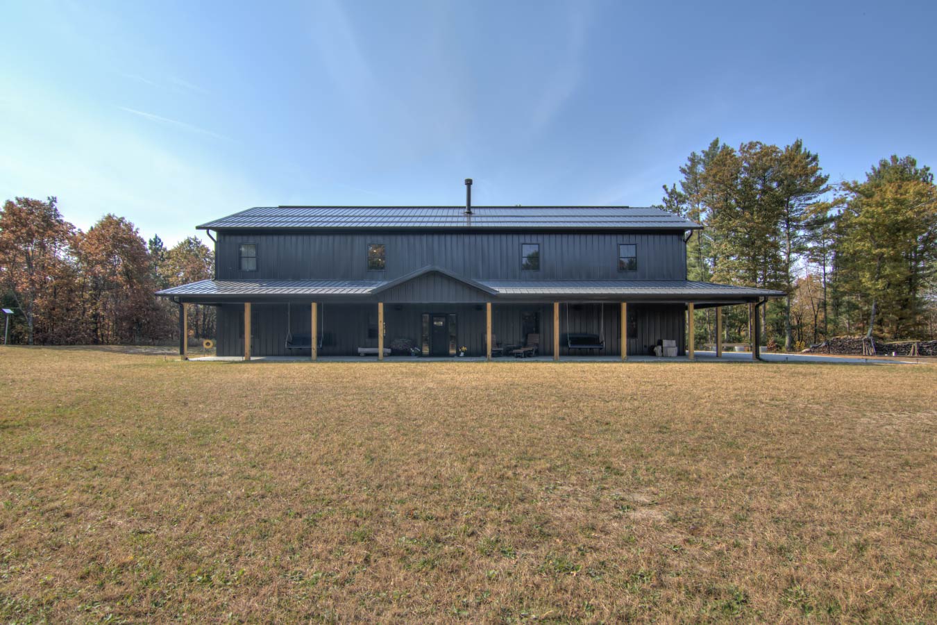 36x72 barndominium with dark steel siding, metal roof, and wraparound porch