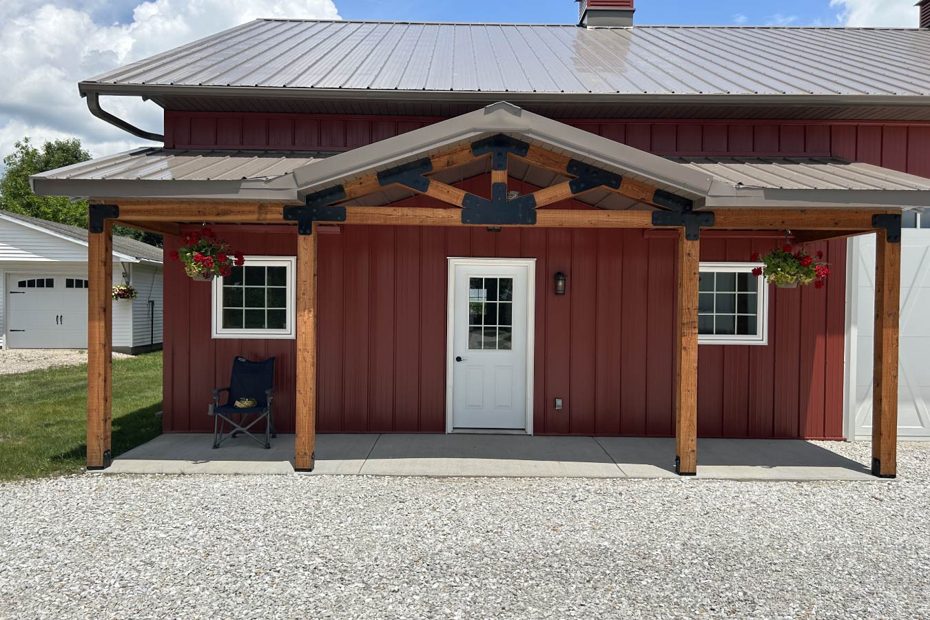 Residential workshop covered porch with wood posts, decorative truss, steel siding, and Plyco windows