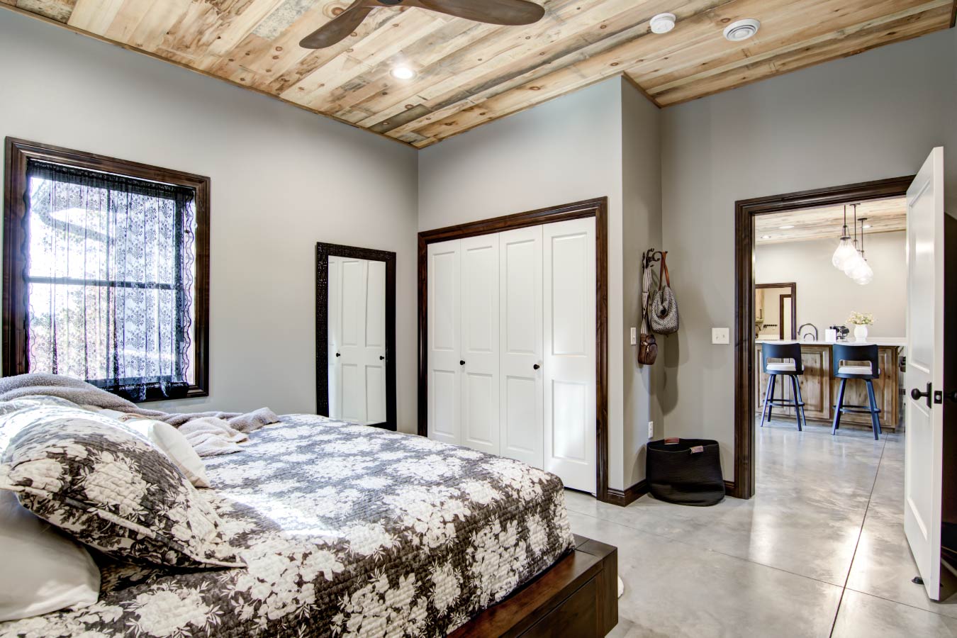 Barndominium bedroom with wood plank ceiling, large window, and walk-in closet doors