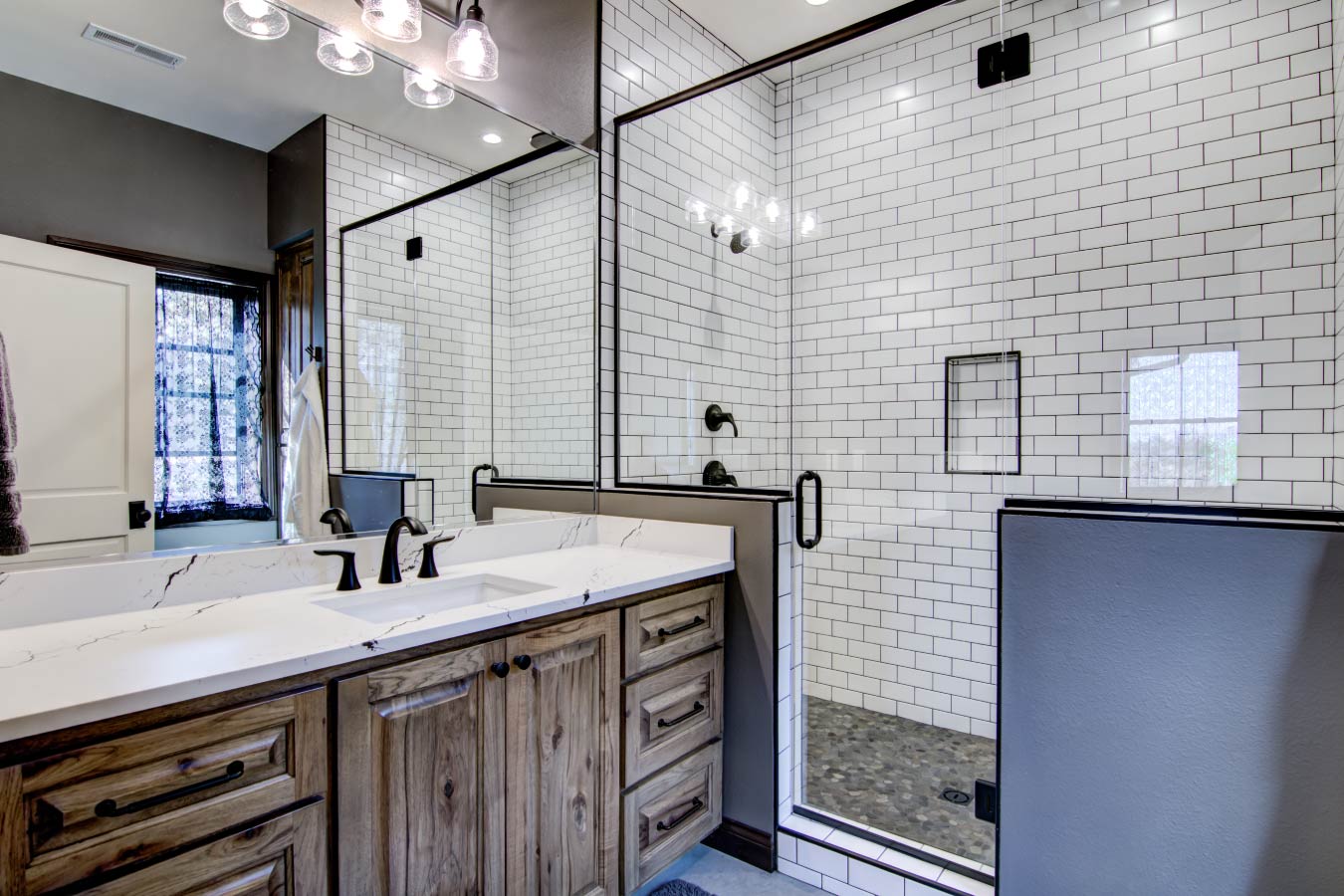 Barndominium bathroom with subway tile shower, glass enclosure, and wood vanity