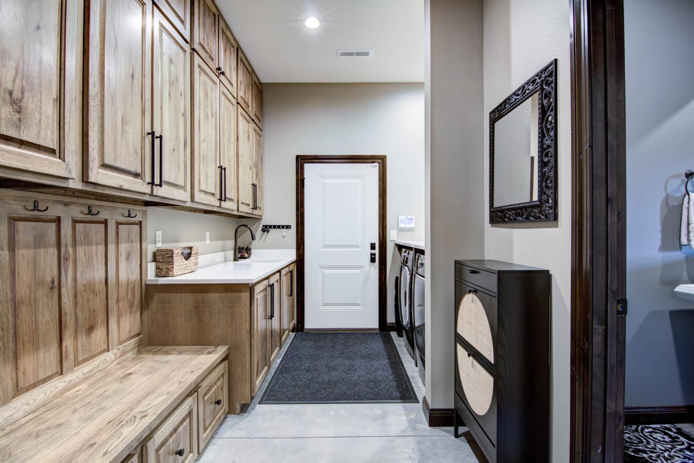 Barndominium mudroom and laundry room with wood cabinets and storage bench