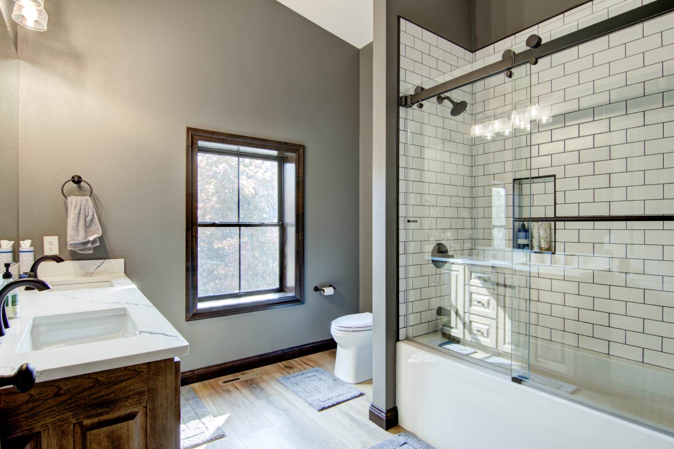 Barndominium bathroom with subway tile tub shower and glass sliding doors