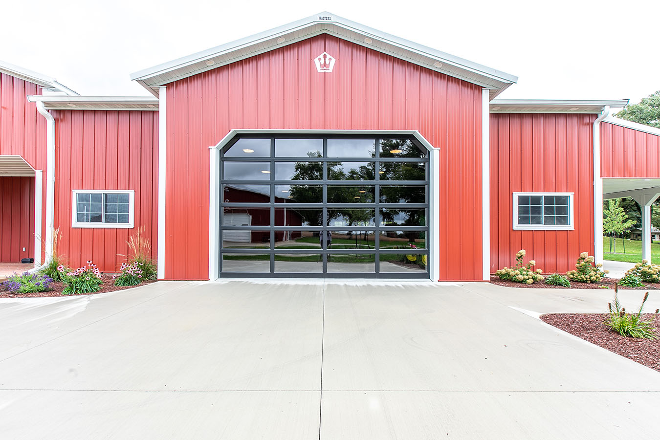 Red pole barn with large black glass garage door and white trim